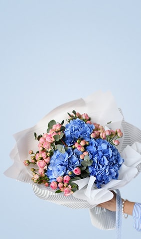 Birthday bouquet with blue hydrangeas and pink roses on light blue background