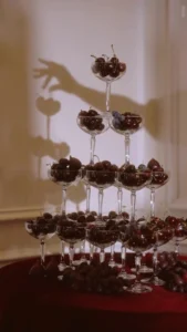 Tiered champagne glass tower filled with fresh dark cherries and grapes at an elegant event