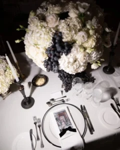 Luxury white floral centerpiece with grapes on elegant wedding reception table setting