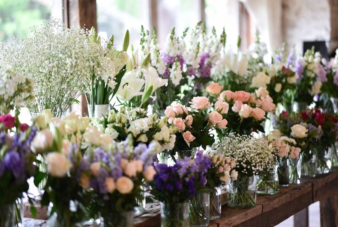 Wedding flower selection with white lilies peach roses baby's breath and purple larkspur in glass vases